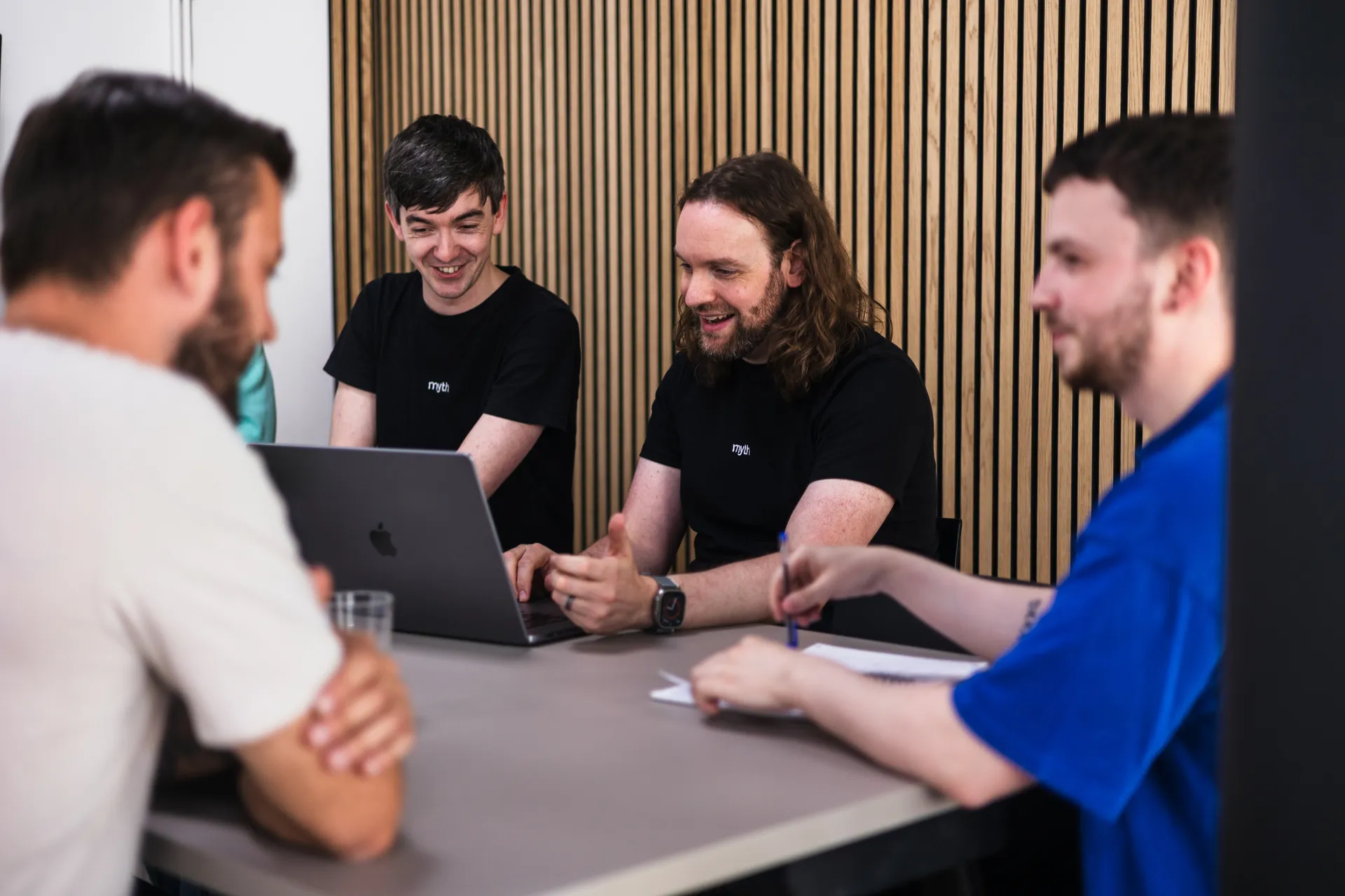 Four team members laughing at a meeting table