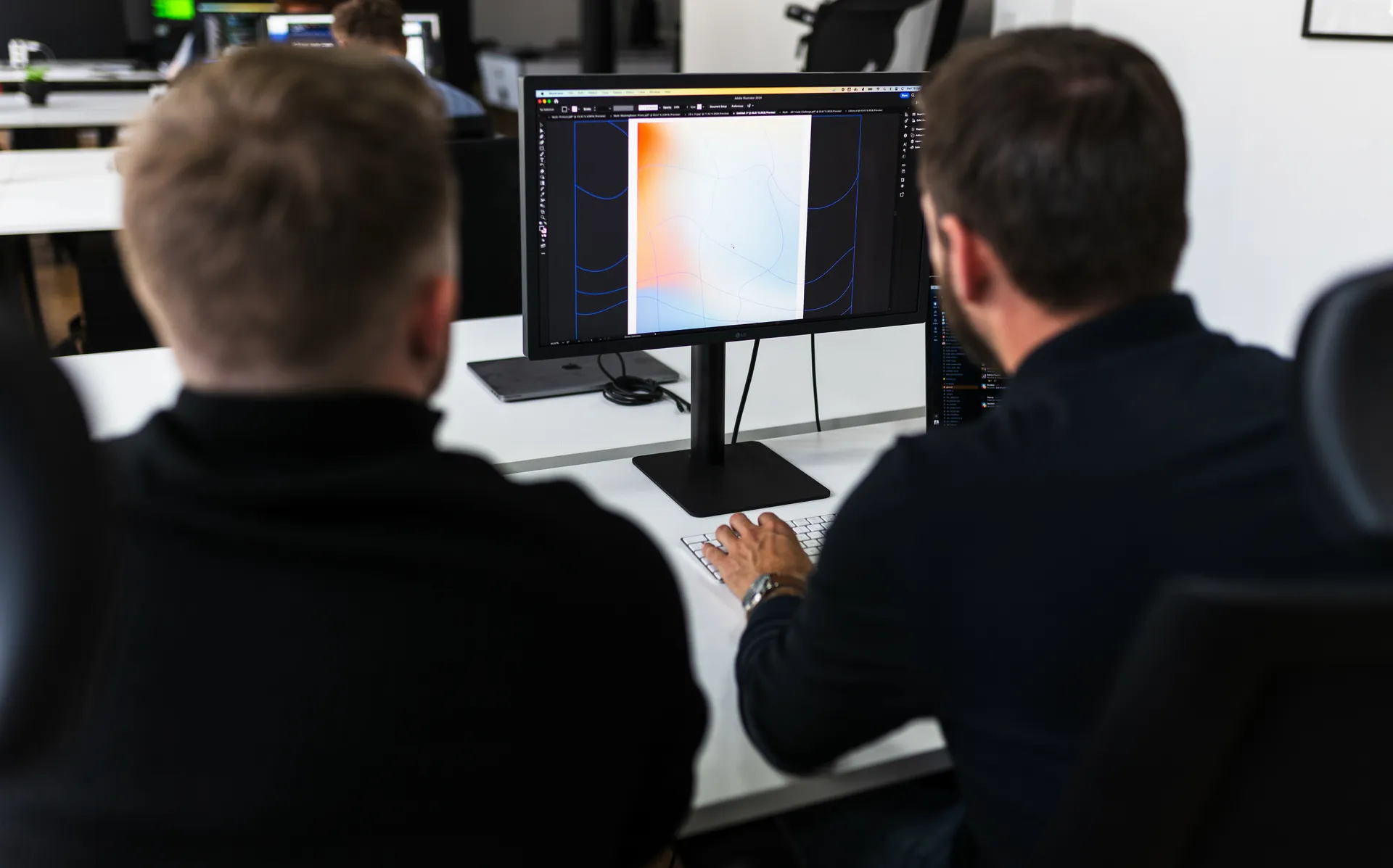 Two developers at a monitor showing a design