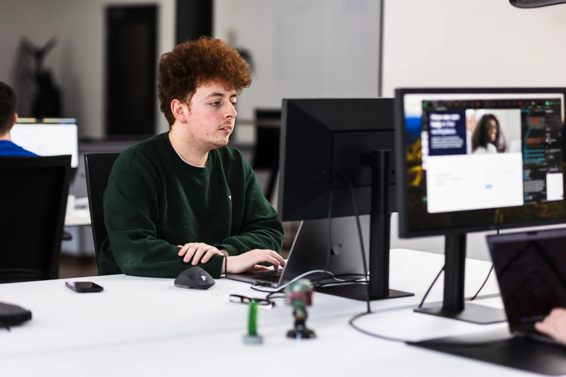 Developer in green at a monitor showing a website