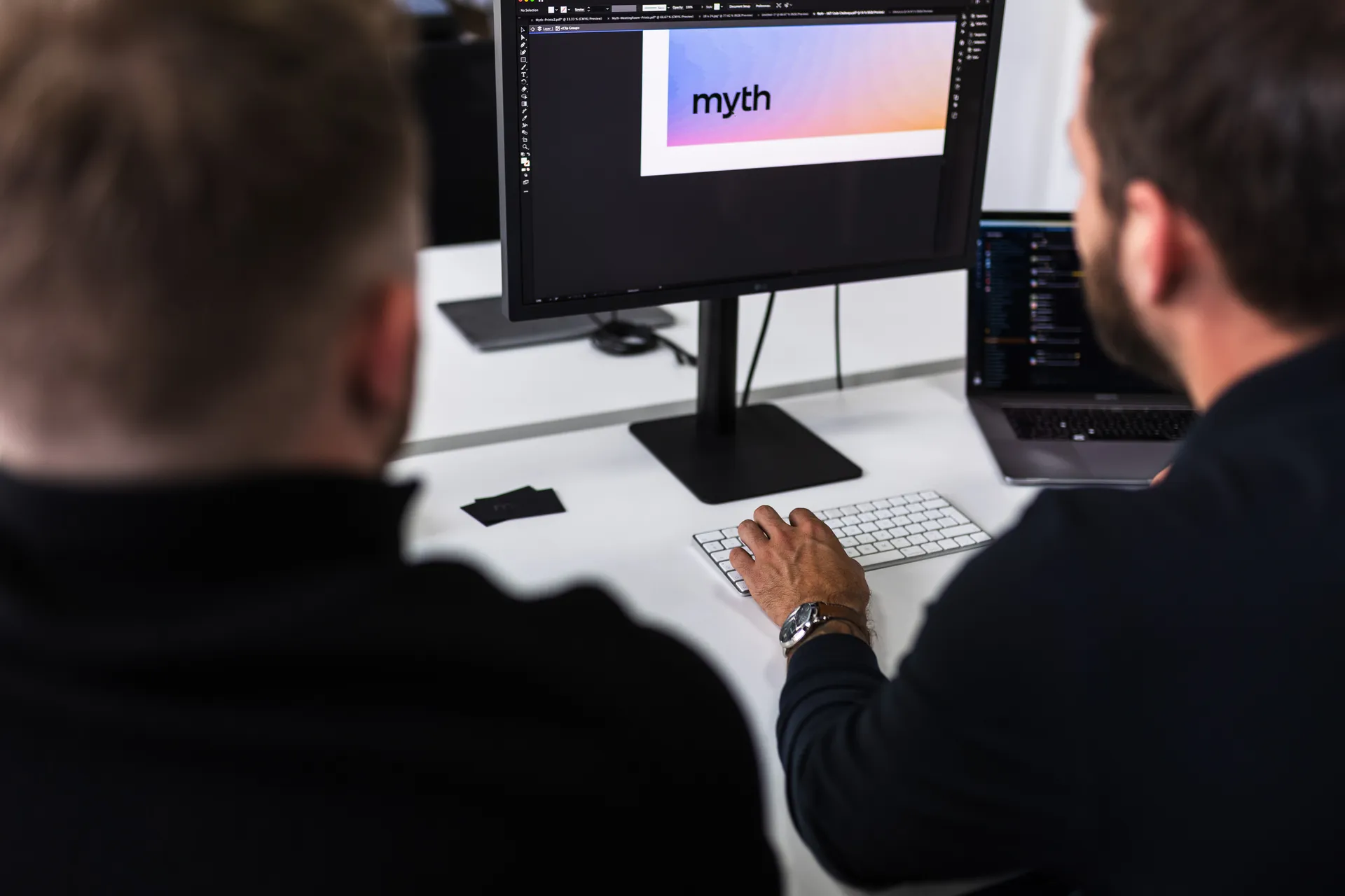 Two people reviewing a Myth design on a monitor