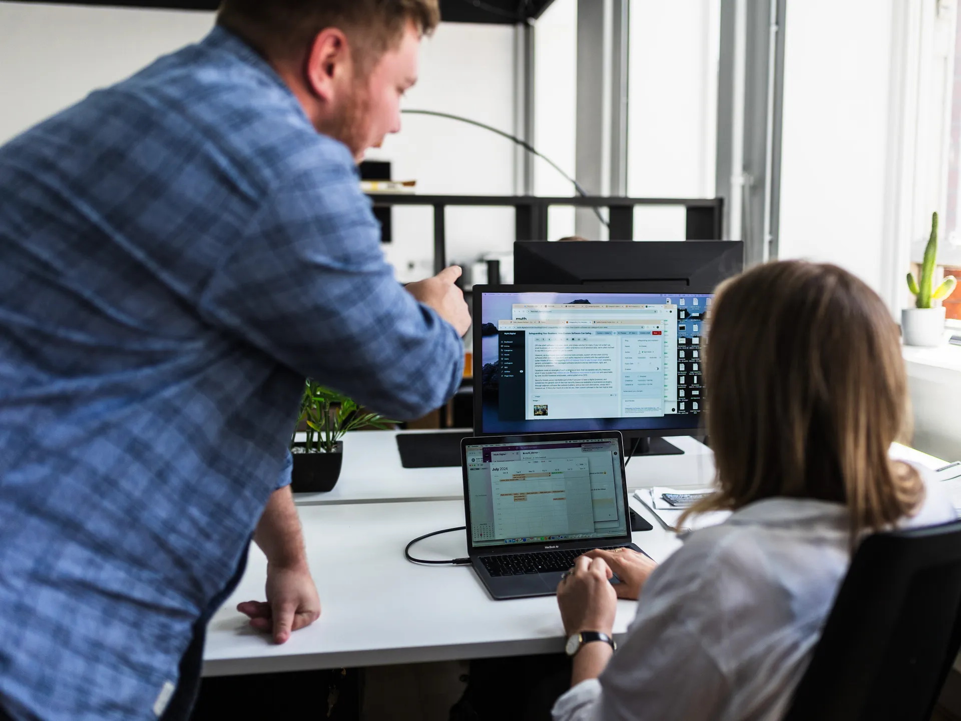 Man leaning in to review a colleague's screen with a dashboard