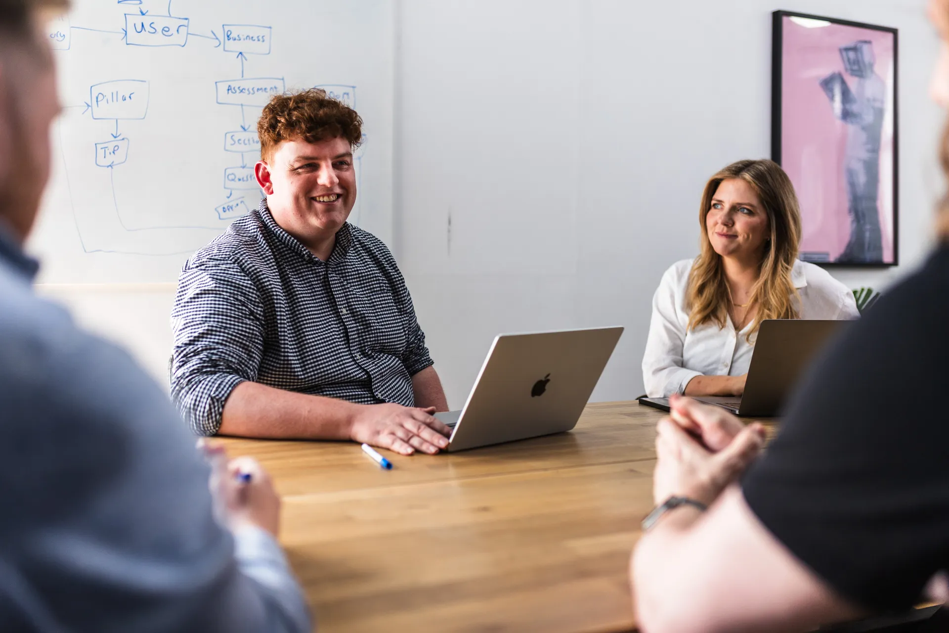 Smiling team at a meeting table with laptops