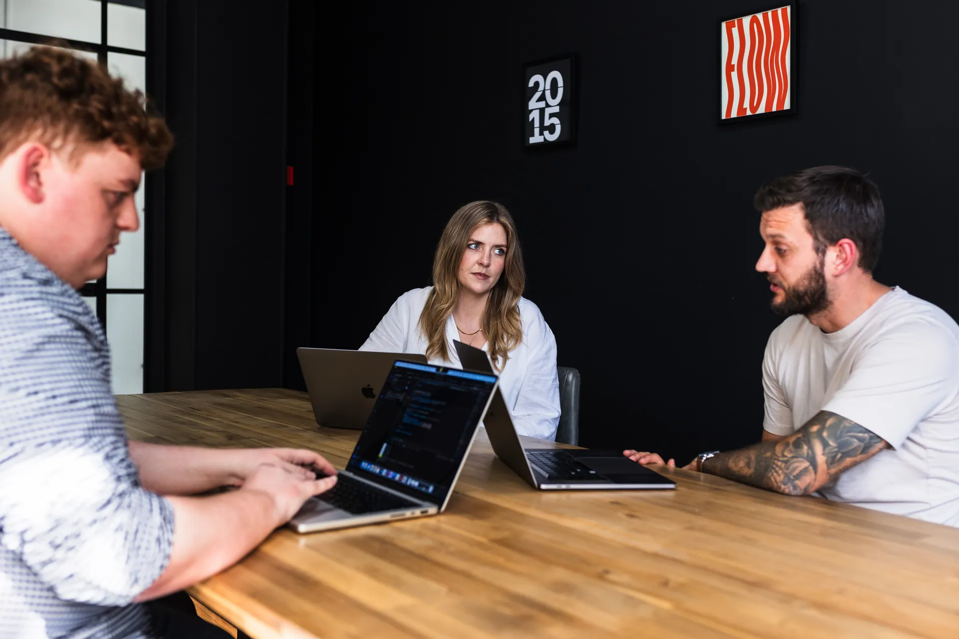 Three people at a table in the dark meeting room with the 2015 print